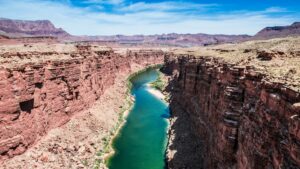 A aerial shot of a bright blue-green river going through a ravine in the Southwest.