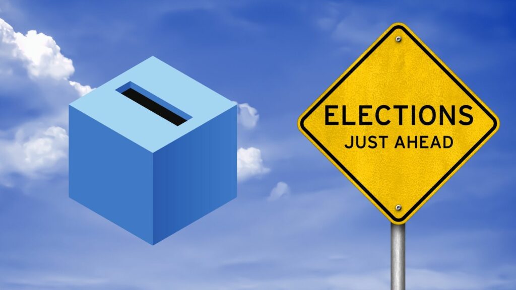 A graphic of a polling box and a yellow sign that says "Elections just ahead" over top a blue sky background.