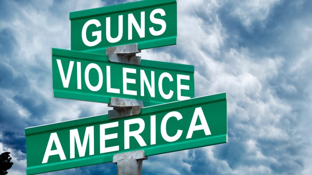 A green street sign that says "guns," "violence," and "America."