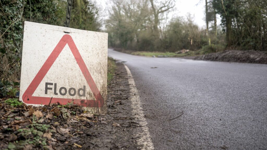 A small sign on the side of the road that says "flood."