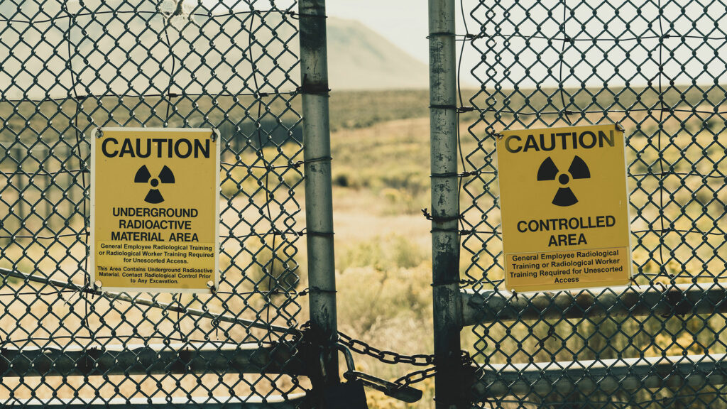 Two caution signs on a chain link fence.