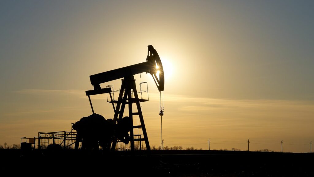 An oil rig silhouetted by a yellow sunset.