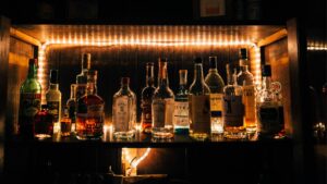 Many bottles of liquor are lined up on a shelf.