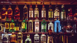 A bar's display of dimly lit shelves of alcohol bottles.