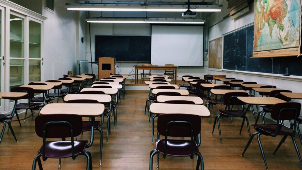 An empty classroom with rows of desks.