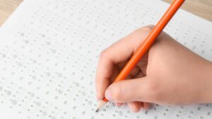 A student marking in the bubbles of a standardized test with a pencil.