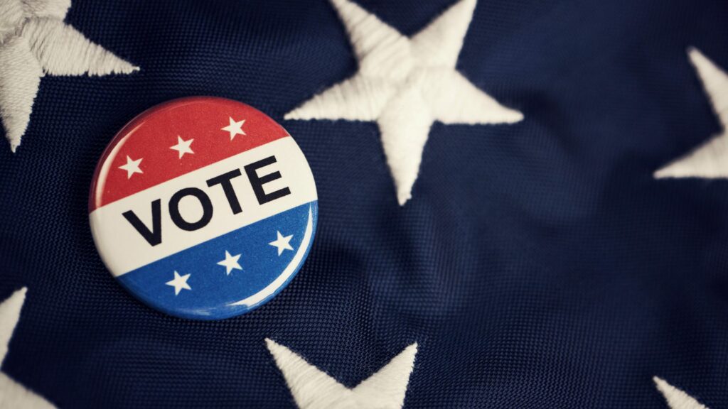 A voting button sitting on the star portion of the American Flag.