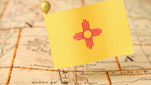 A small New Mexico flag on a pin stuck in a map of New Mexico.