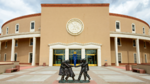 A statue of two people holding hands in front of a tan building.