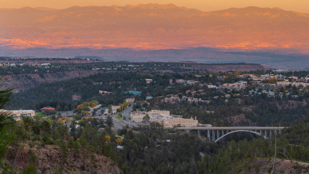 A view of a city at sunset with mountains in the background.