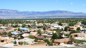 An overview shot of a neighborhood and the Sandia Mountains behind them.