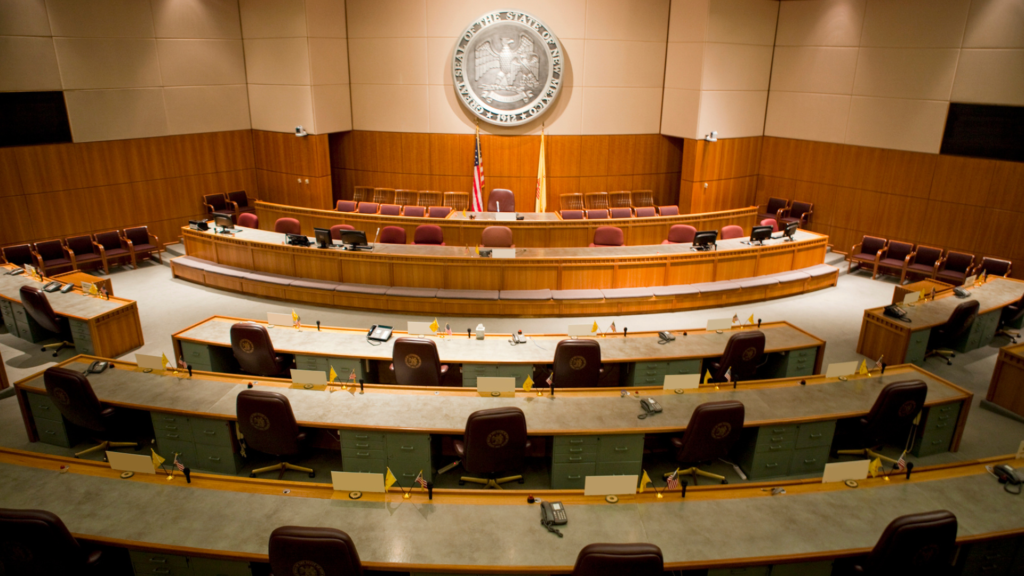 An empty courtroom with chairs and a clock.