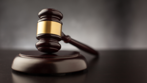 A wooden gavel lying on a black table.