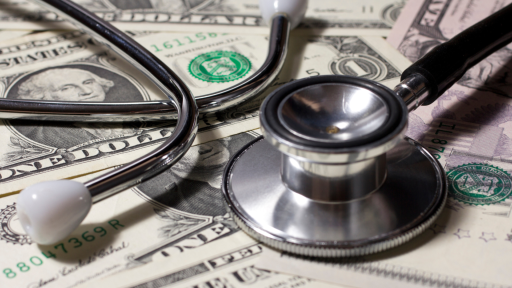 A stethoscope sits on top of a pile of money.