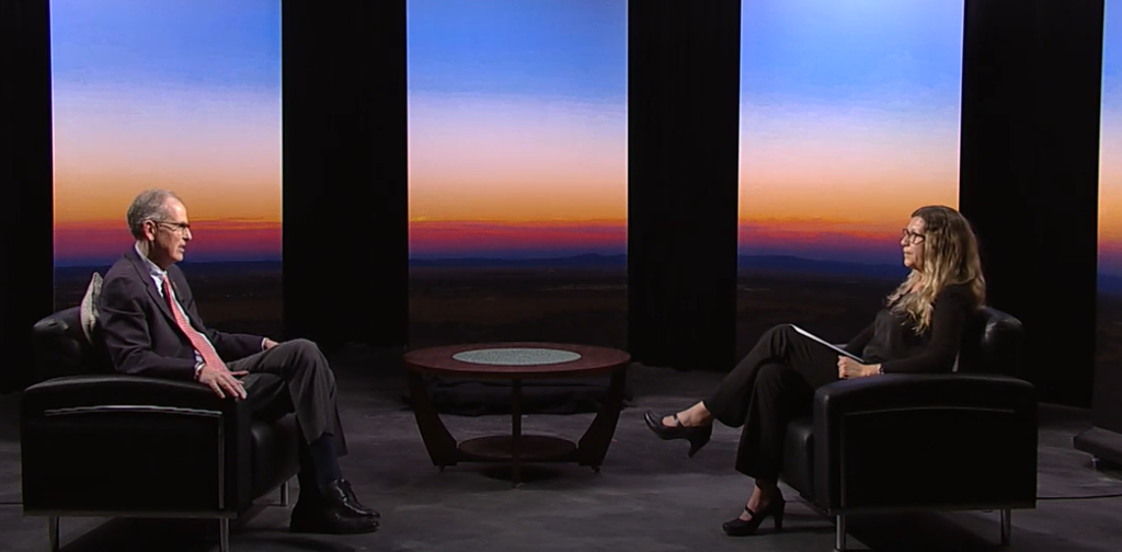 A man and woman sitting in chairs in front of a sunset.