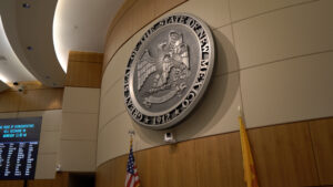 A close up of the state seal hanging up on the wall above the flags in the Roundhouse.