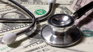 A stethoscope sits on top of a pile of money.