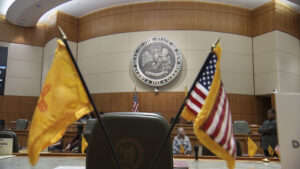 Two american flags on a desk in a courtroom.