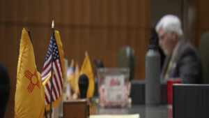 A man sits at a table with flags in front of him.