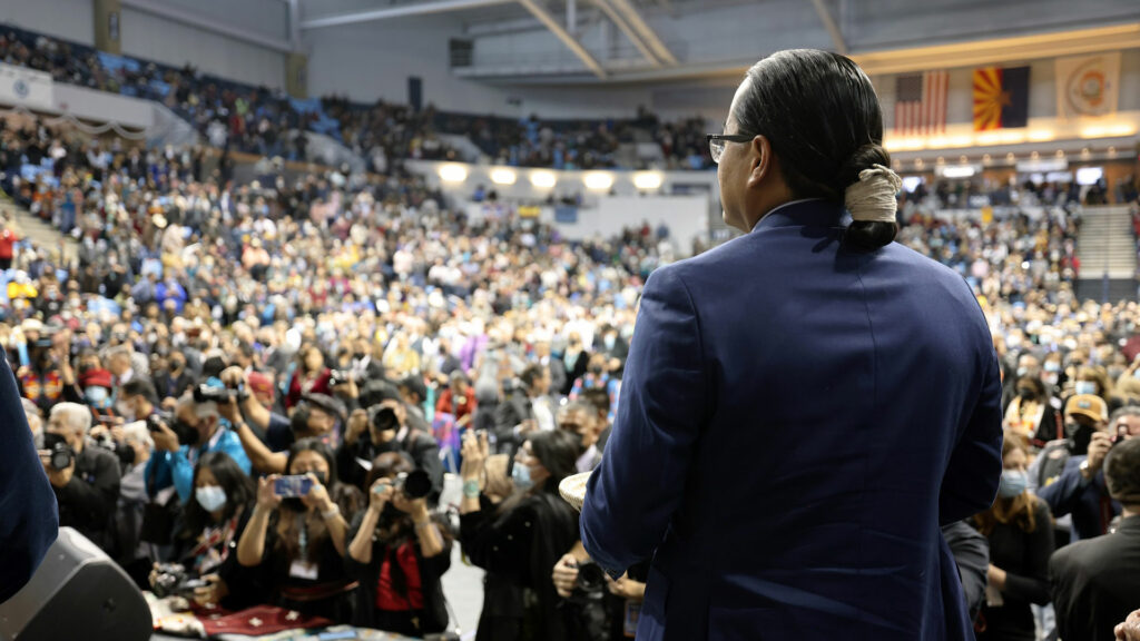 A man in a suit standing in front of a crowd.