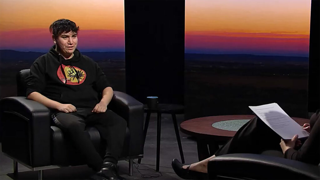 A man sitting in a chair talking to a woman.