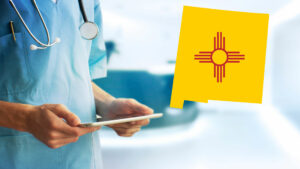 A nurse or doctor looking at a chart with an image of the New Mexico state shape and zia symbol.