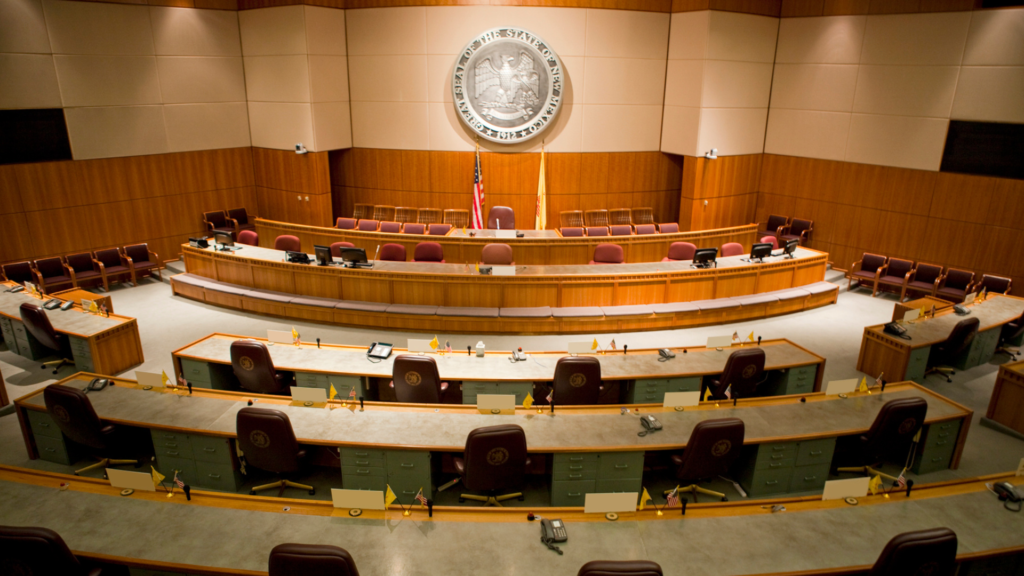 An empty courtroom with chairs and a clock.