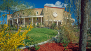 A tan building with yellow flowers in front of it.