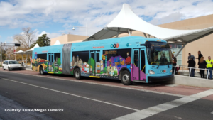 A blue bus is parked in front of a building.