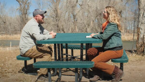 New Mexico Wildlife Federation Executive Director Jesse Deubel sitting on a park bench with Laura Paskus.