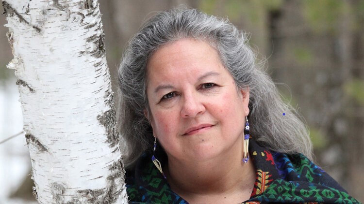 A woman leaning against a birch tree.