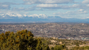 A view of a city with snow capped mountains in the background.