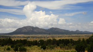 A view of mountains and trees with clouds in the sky.