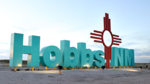 A sign that says hobbs nm in front of a beach.