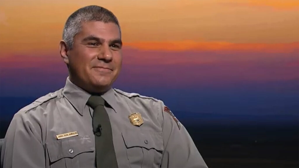 A man in a uniform sitting in front of a sunset.