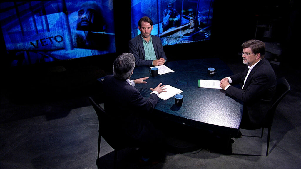 Three men sitting at a table.