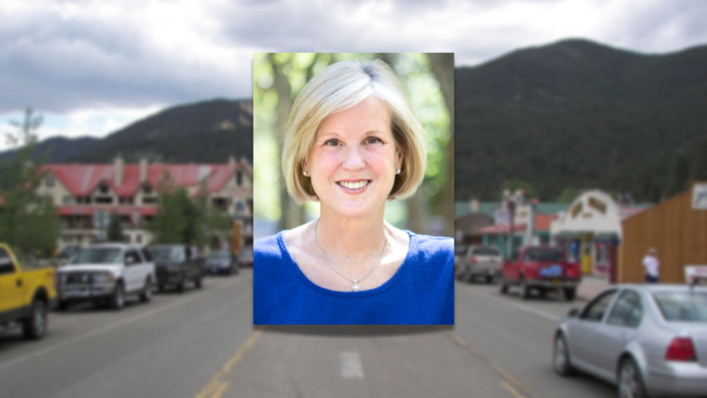 A photo of a woman in front of a street with mountains in the background.