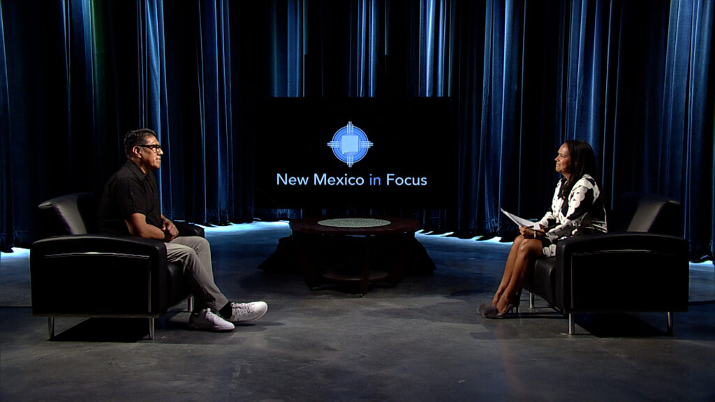 A man and woman sitting in chairs in front of a television.