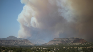 A smoke plume rises over a mountain range.