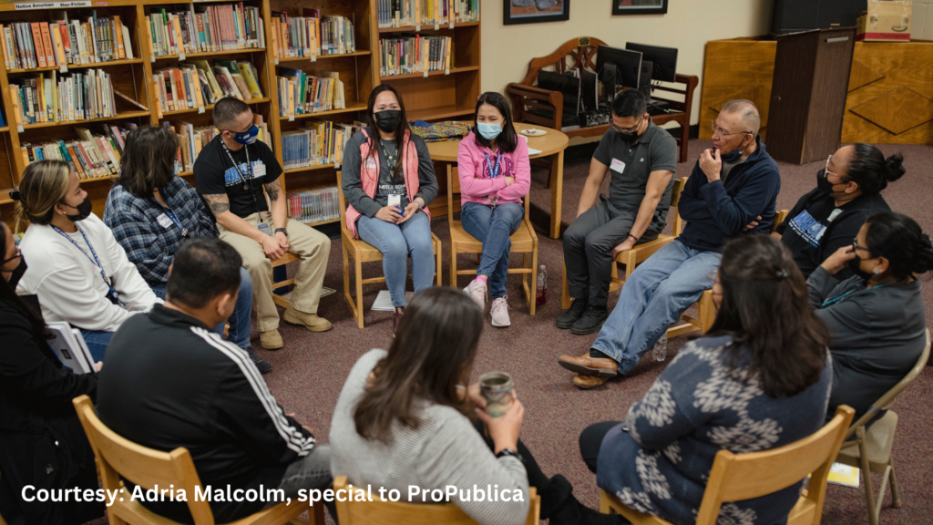 A group of people sitting in a circle in a library.