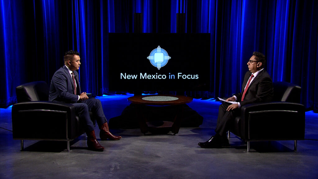 Two men sitting in chairs on a stage with the words new mexico's food.