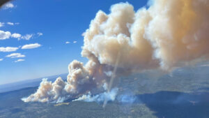 A smoke billows from a waterless fire in the mountains.