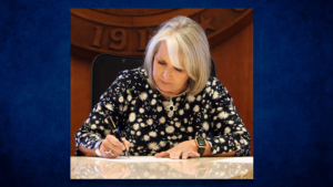 A woman signing a document at a desk.