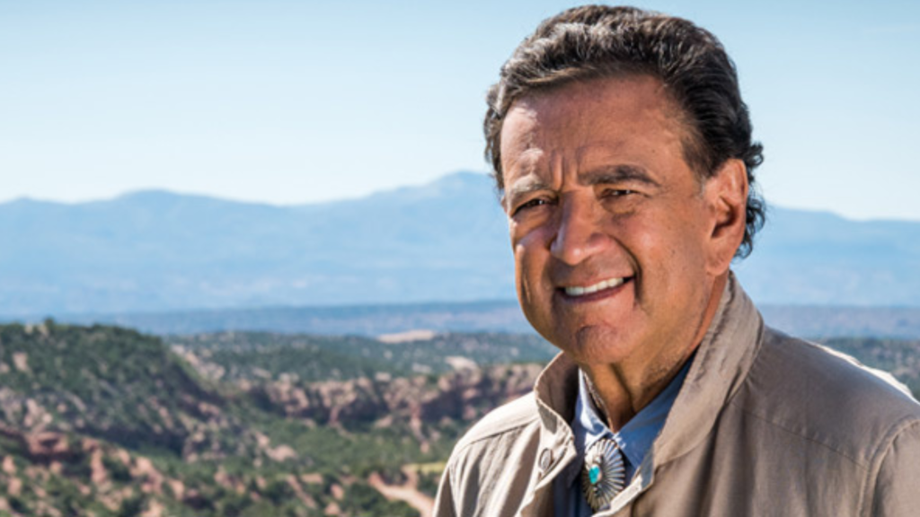 A man smiling in front of a mountain.