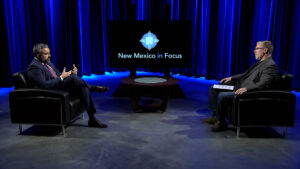 Two men sitting in chairs on a stage.