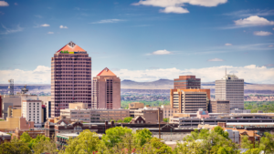 A city skyline with trees and mountains in the background.