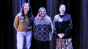 Three women standing in front of a curtain.