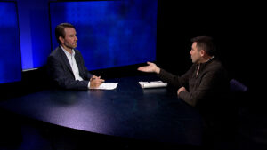 Two men sitting at a table talking to each other.