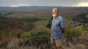 A man with a beard standing on top of a hill.