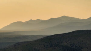 A mountain range is seen in the distance at sunset.